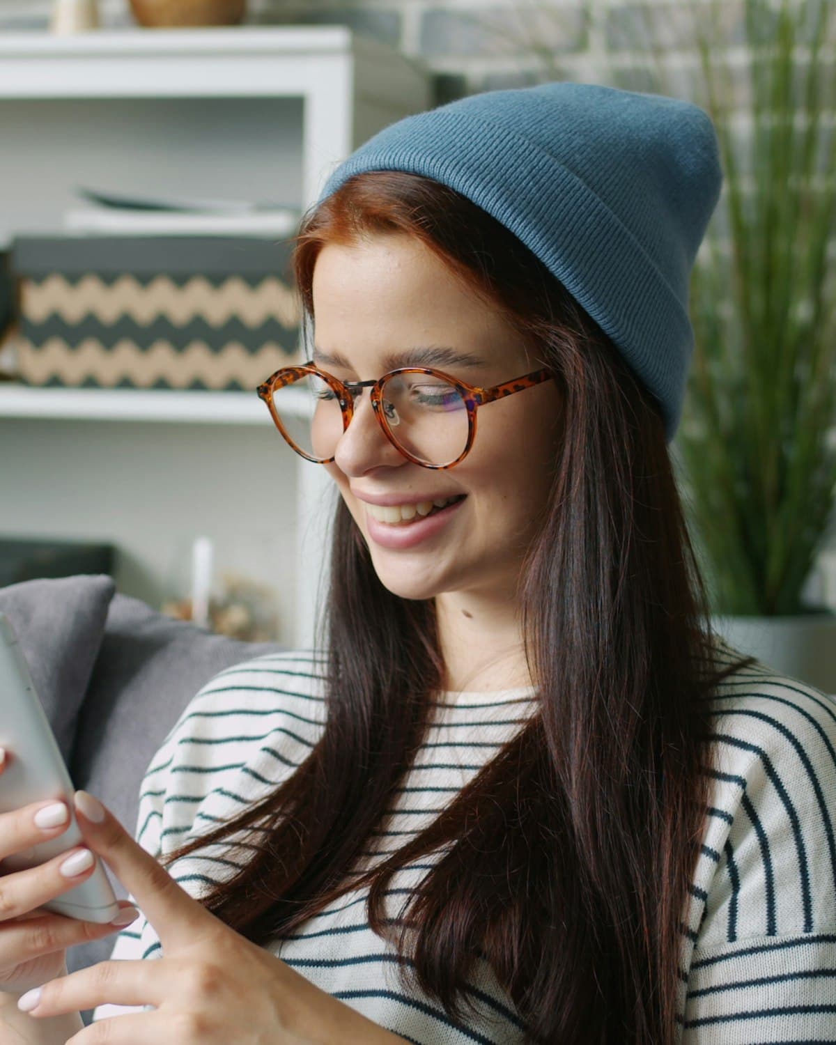 A woman in a beanie smiling at her phone while learning with Astra Trainer