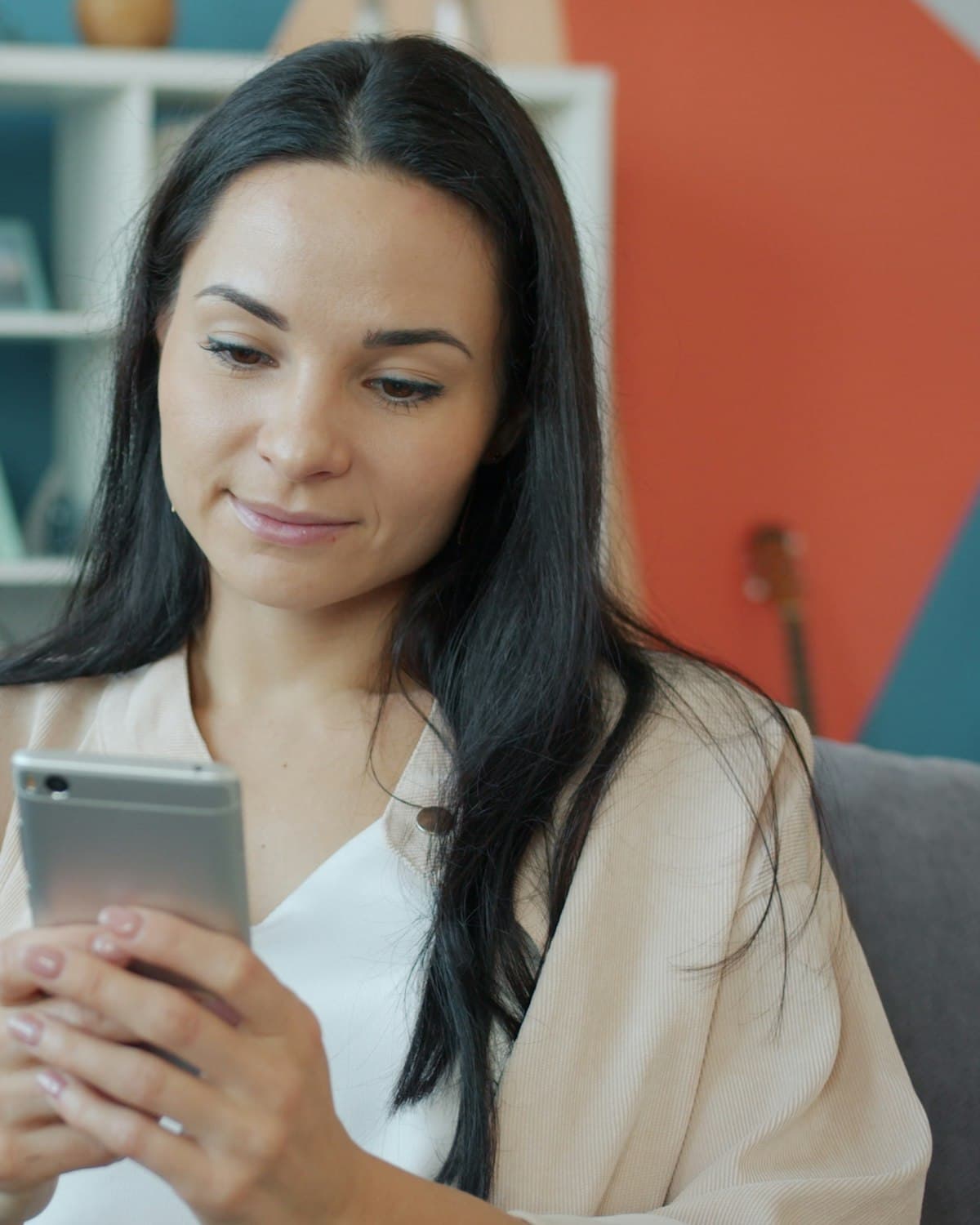 A woman on the sofa smiling at her phone while learning with Astra Trainer