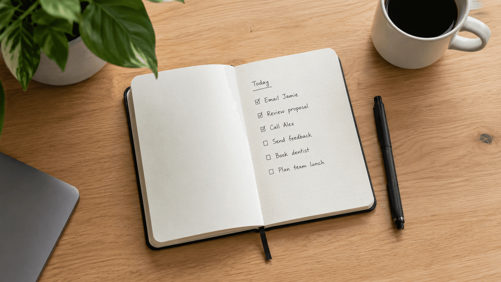 Overhead flatlay of a desk with a small notebook open to a short checklist, pen resting beside it
