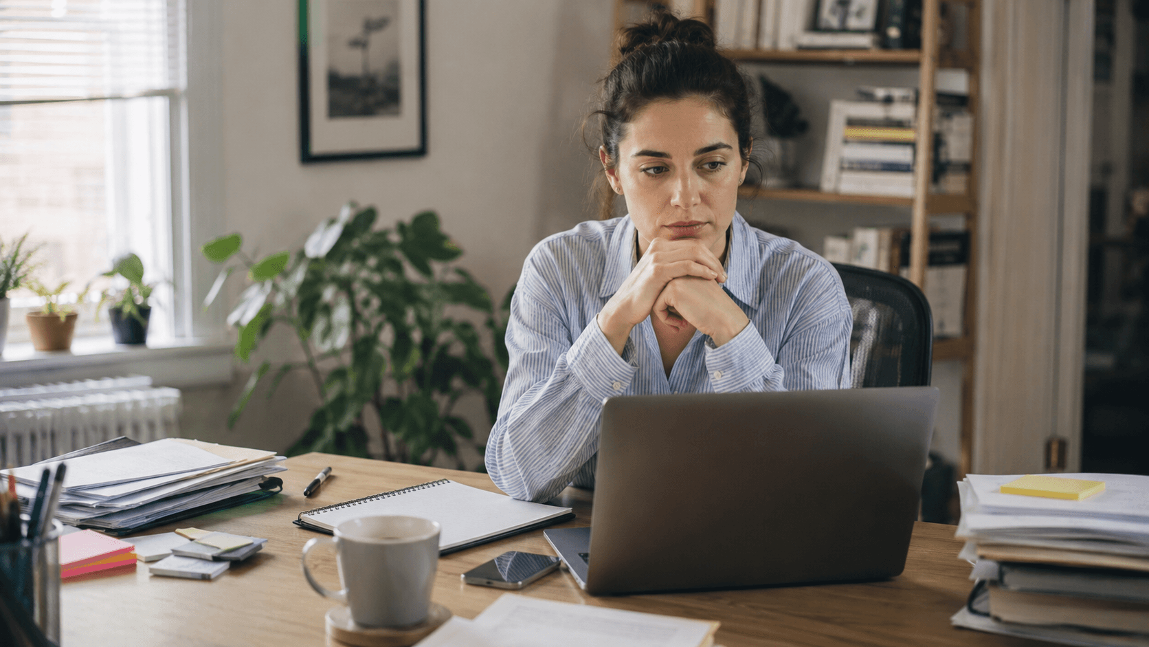 A person pausing before an important task on a laptop while smaller completed tasks sit around the desk