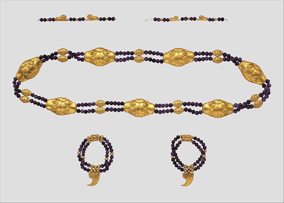 Ancient Egyptian gold jewellery strung with dark purple amethyst beads: a girdle with gold feline heads, and two anklets