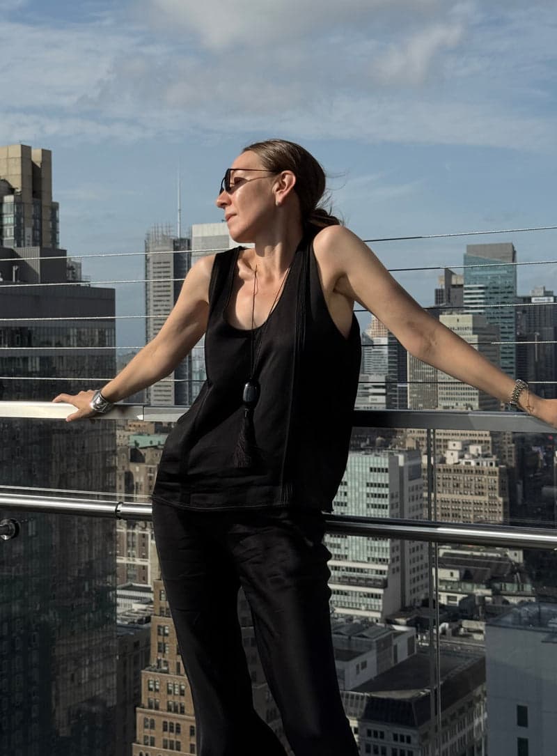 The black obsidian tassel pendant worn over a black outfit on a rooftop