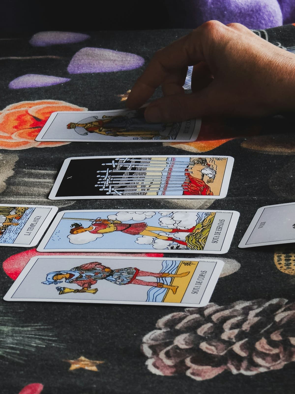 Manos colocando cartas de tarot en fila sobre una tela oscura durante una lectura