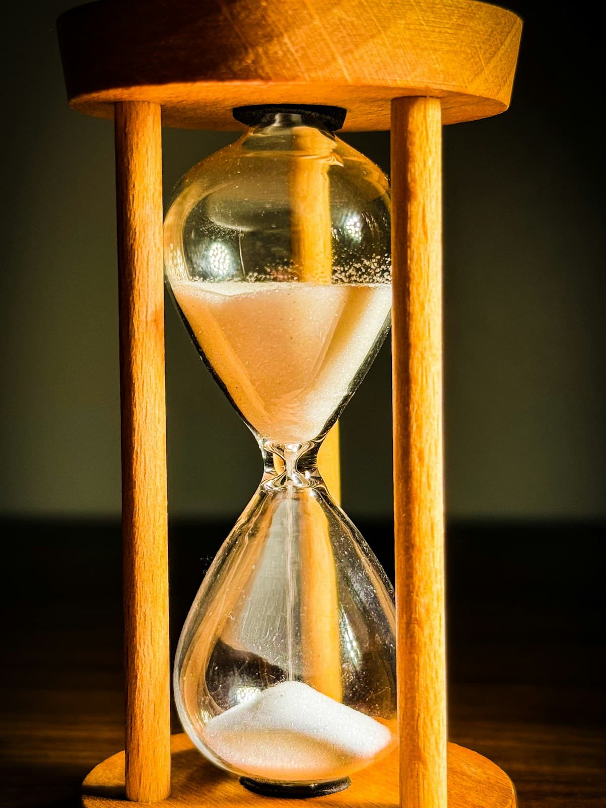 Un reloj de arena de madera con arena cayendo sobre un escritorio