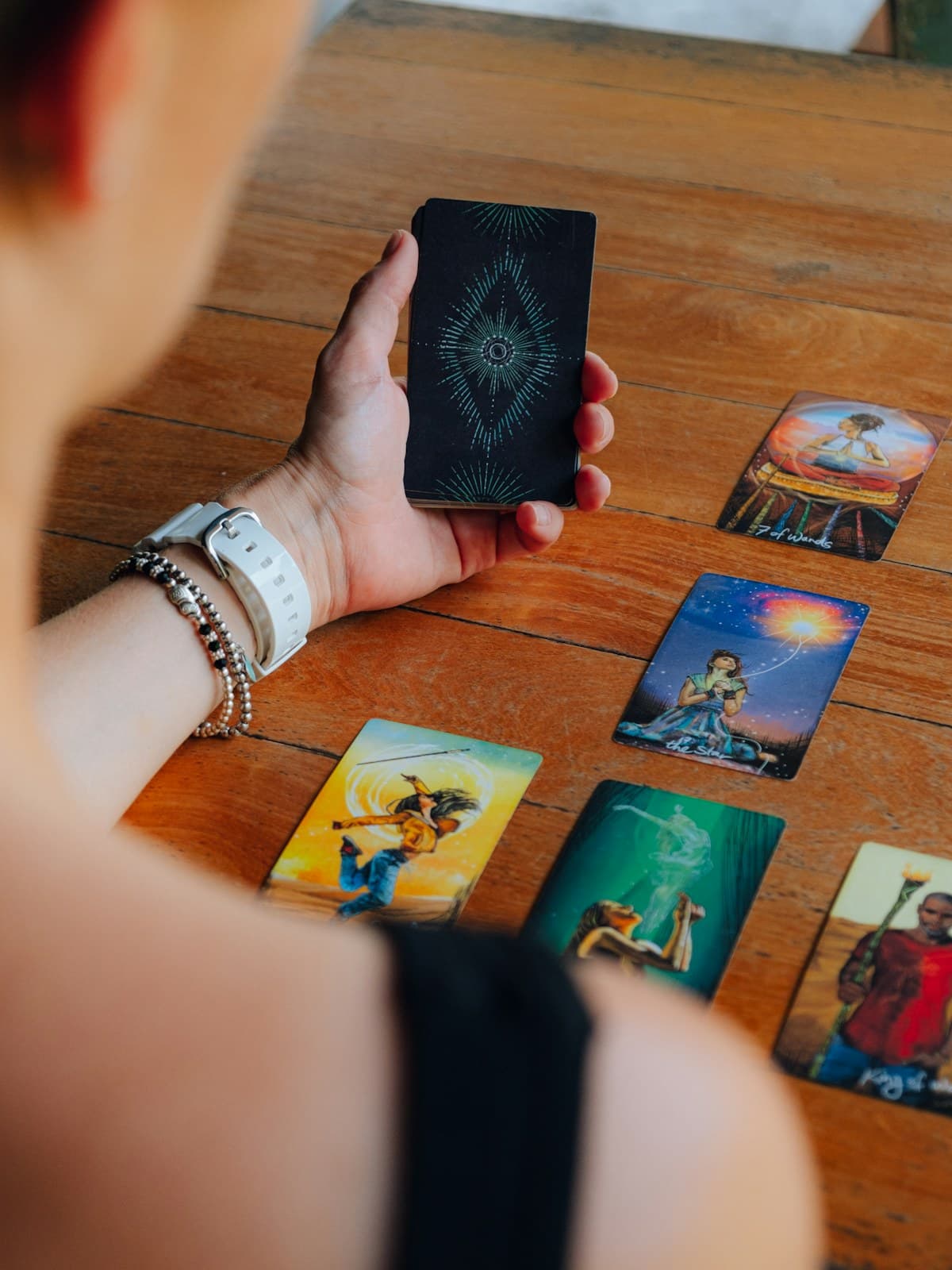 A person holding a phone over tarot cards laid out on a wooden table