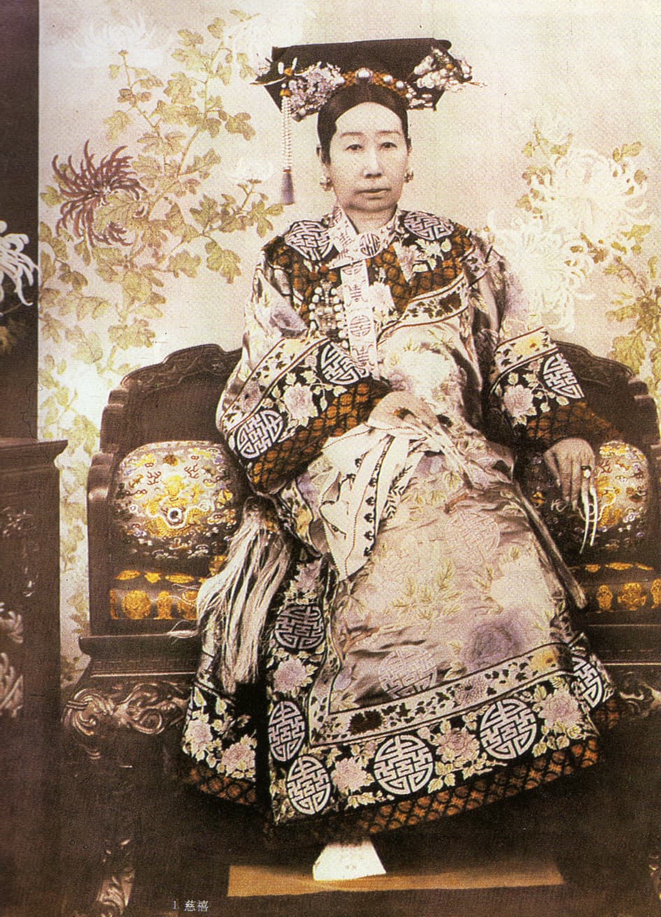 A hand-coloured photograph of the Empress Dowager Cixi seated on a carved throne in an embroidered robe