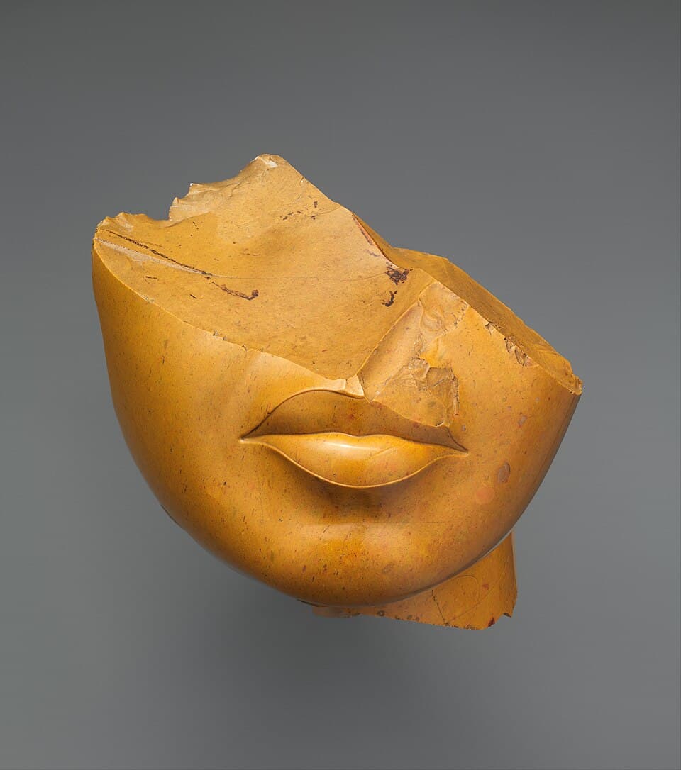 A polished yellow stone fragment showing only the lips and chin of a woman's face