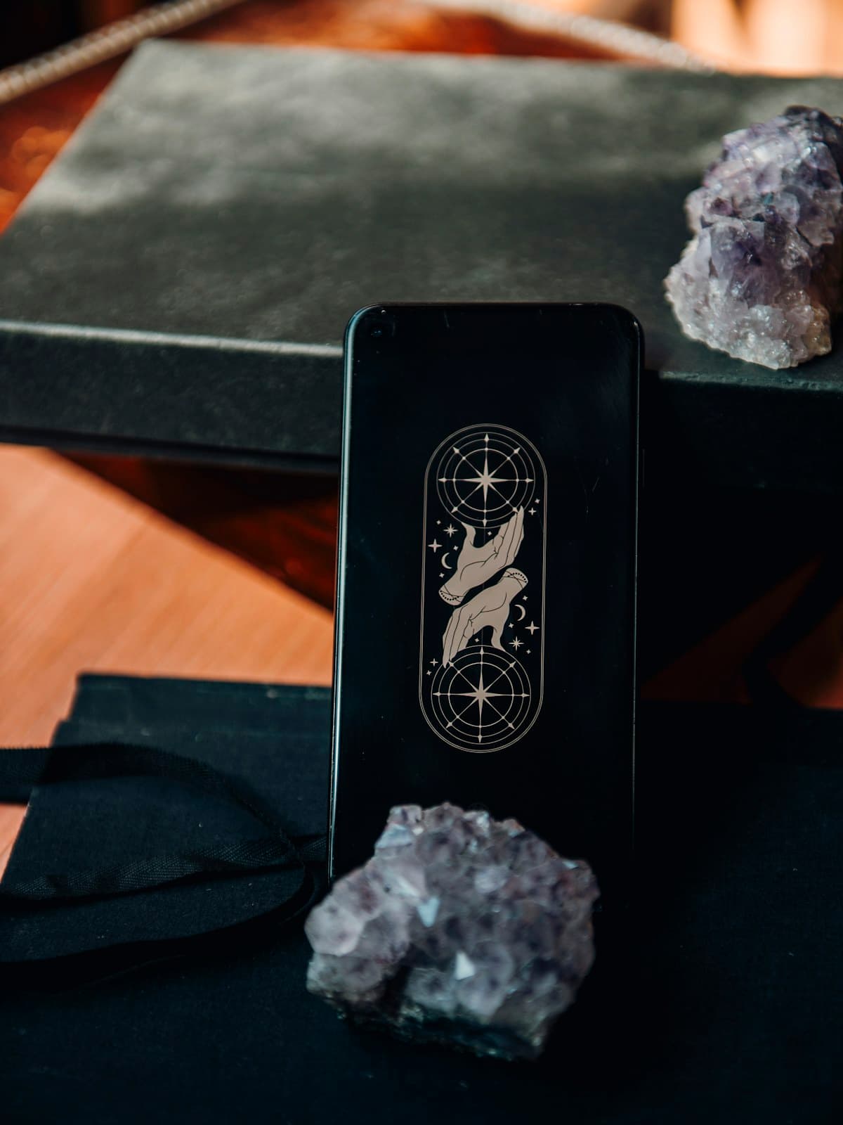 Una baraja de tarot sobre un cuaderno oscuro junto a dos cristales