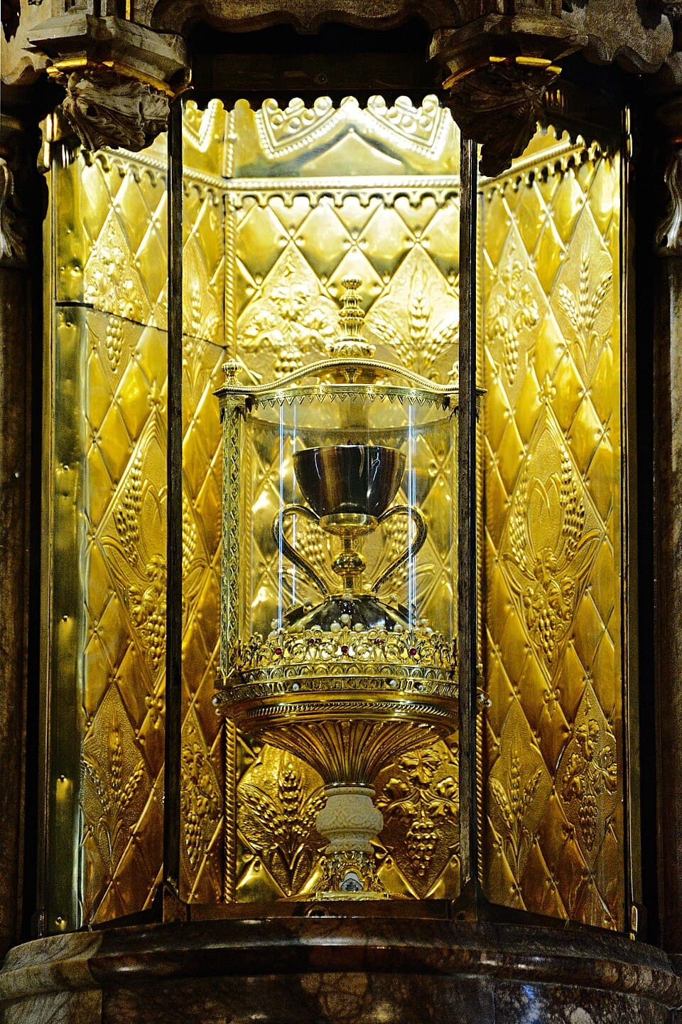 A small chalice on a gold stand inside an ornate gilded Gothic shrine in Valencia Cathedral