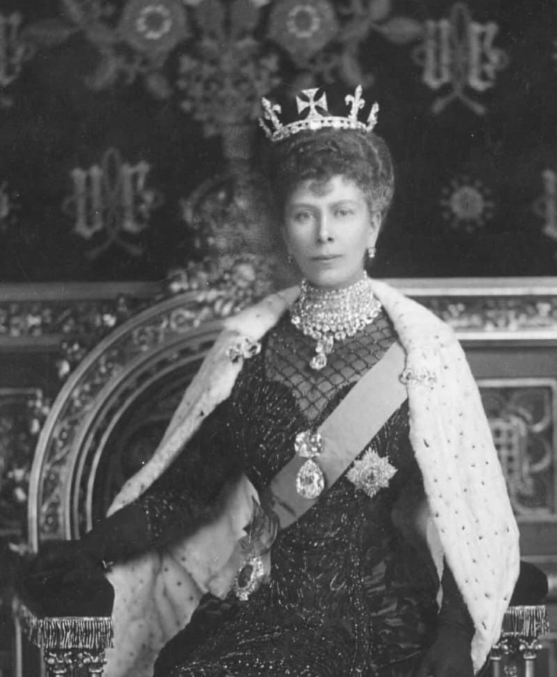A black and white photograph of Queen Mary wearing a diamond crown, necklaces and a sash